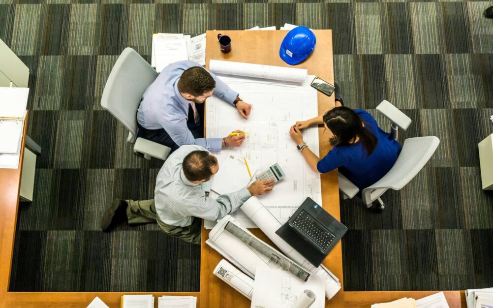 Aerial view of a team seated at a table looking over a site plan discussing a construction project